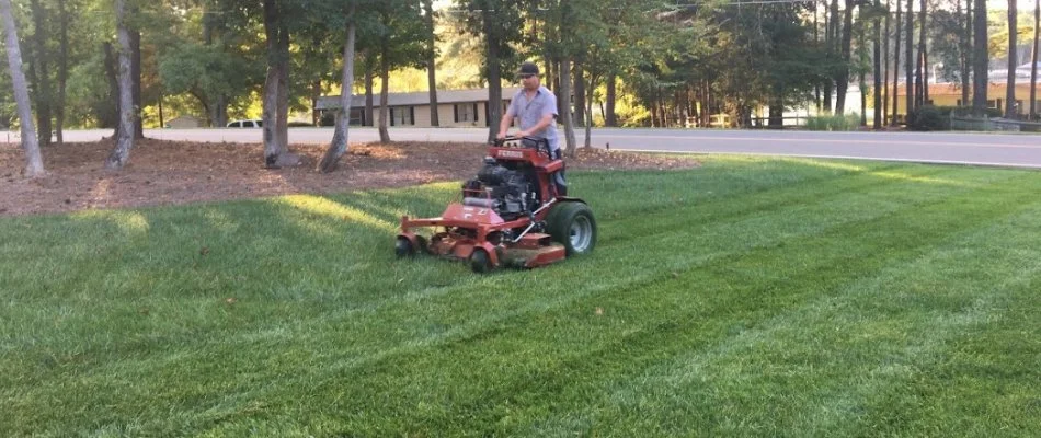 Worker in Charlotte, NC, mowing a lawn.
