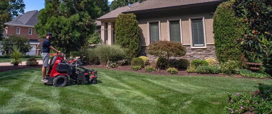 Crew operating an aerator machine across a lawn in Charlotte, NC.