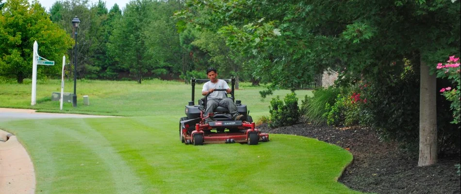 Employee mowing a green lawn for an HOA in Harrisburg, NC.