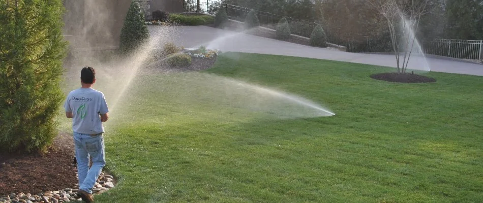 Professional walking through a lawn with sprinklers in Charlotte, NC.