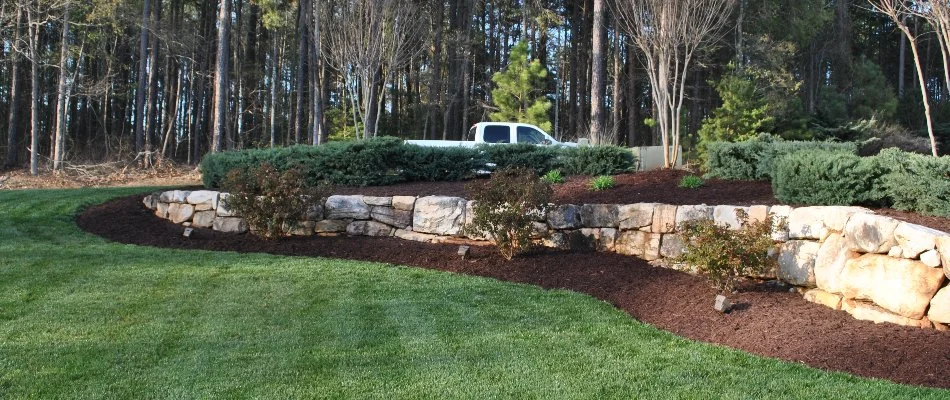 Retaining wall in Pineville, NC, with mulched landscape bed and shrubs.