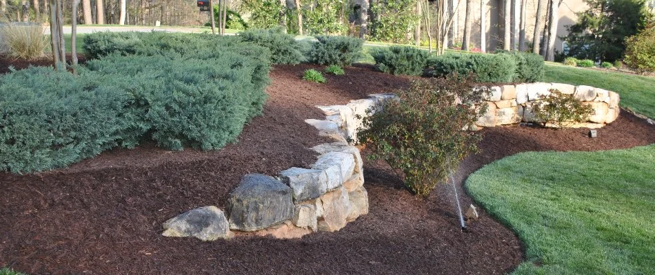 Retaining wall in Waxhaw, NC, with mulched planter bed and shrubs.