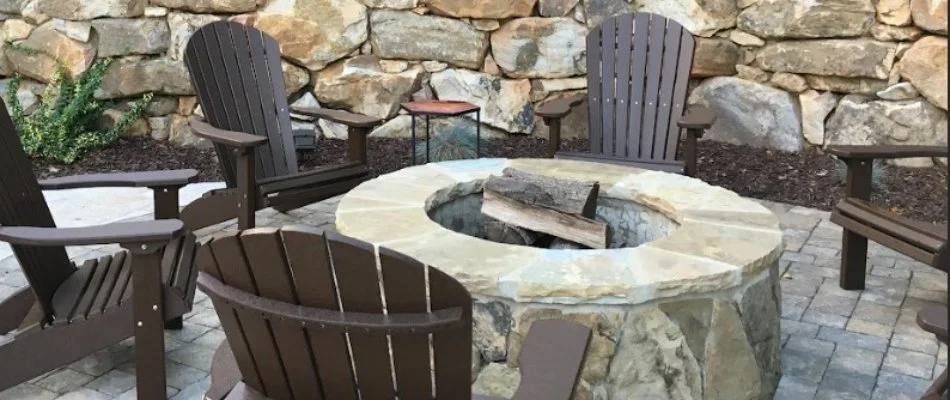 Round fire pit in Charlotte, NC, with wood surrounded by chairs.