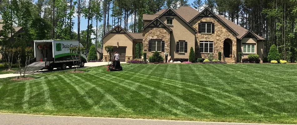 A worker in Charlotte, NC, maintaining the front lawn of a house.