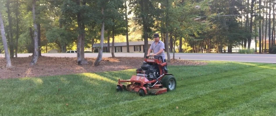 Worker mowing a lawn in Pineville, NC.